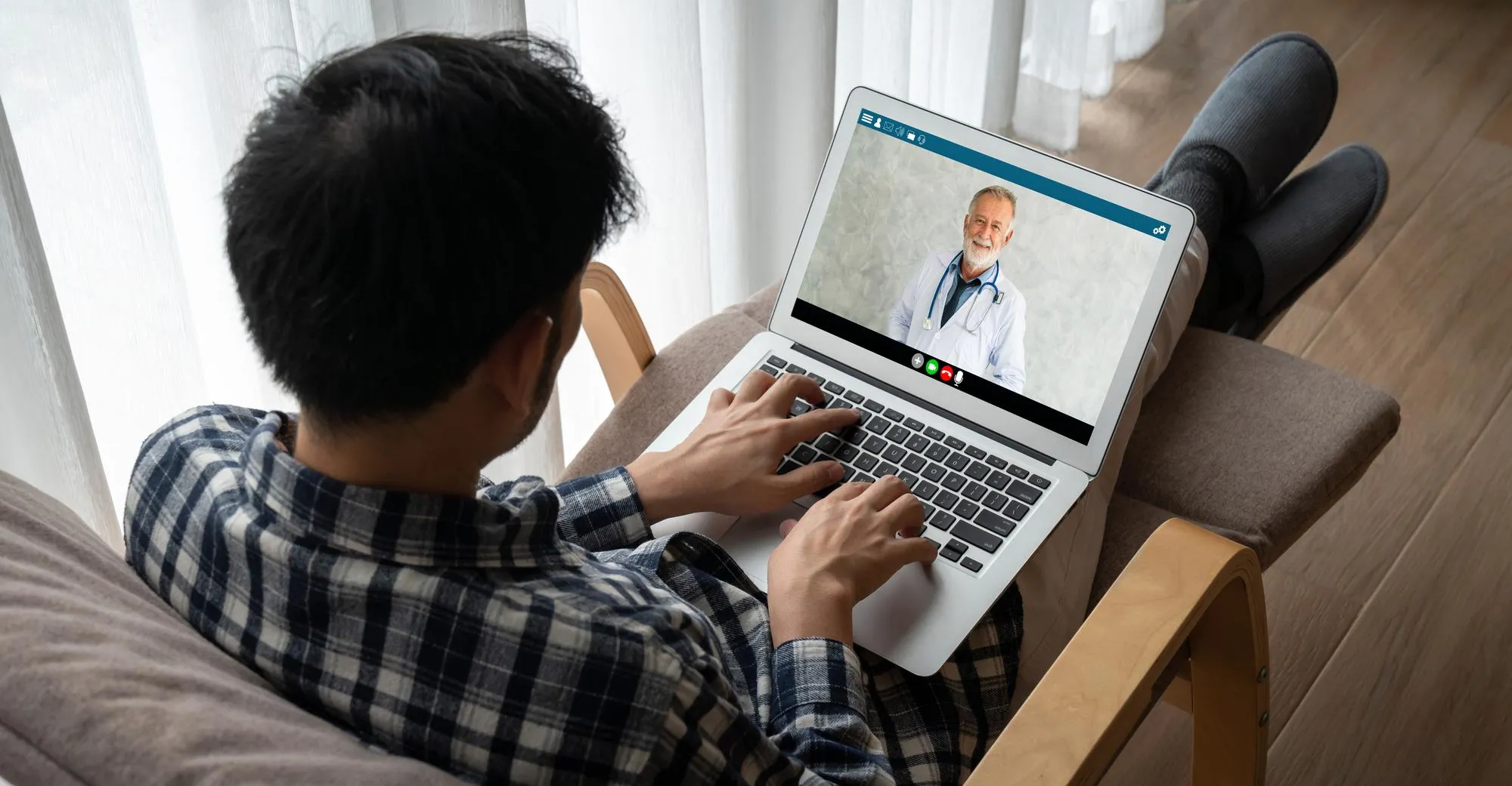 Patient attending a virtual healthcare visit with a doctor through a laptop from home.