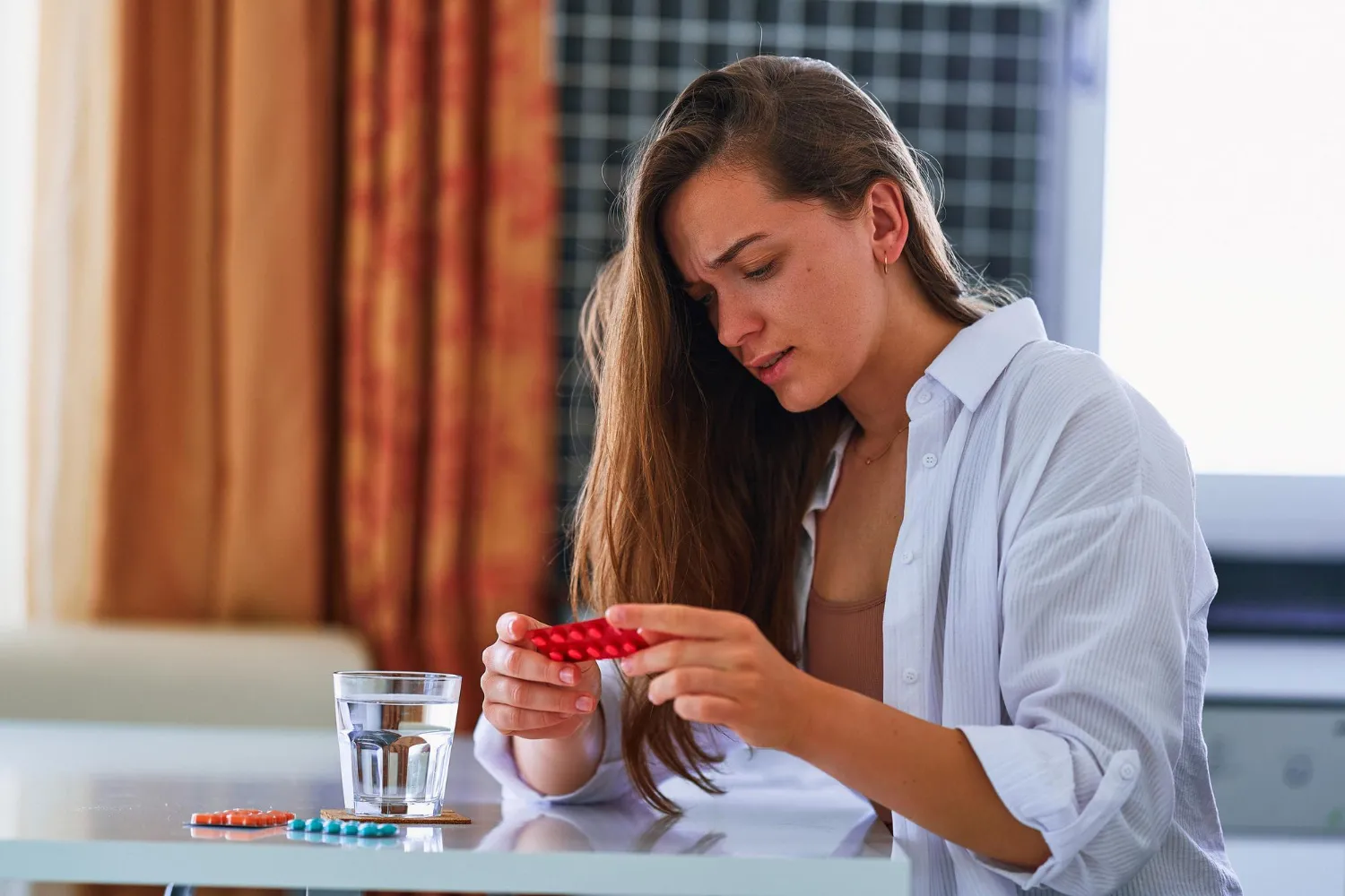 Patient examining hormone replacement therapy pills with water, managing HRT treatment at home