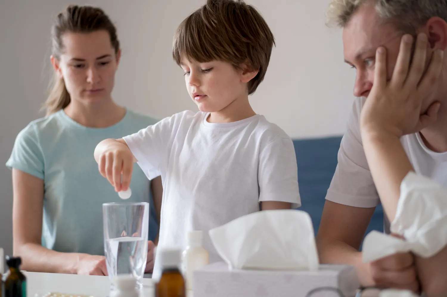 Young child taking customized medication with parents during pediatric compounding pharmacy treatment