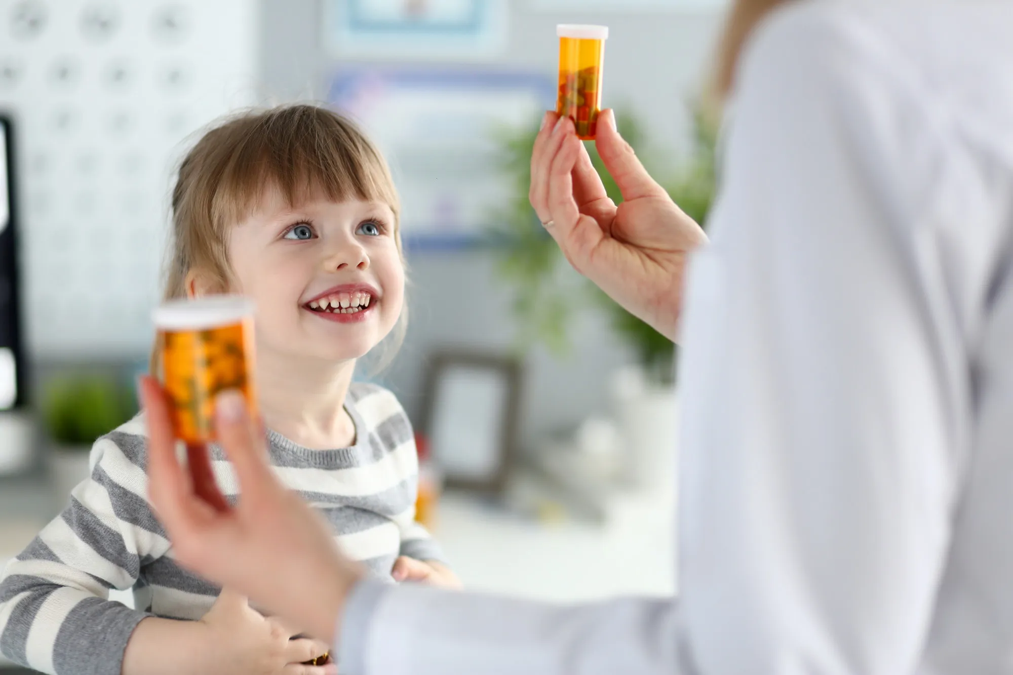 Pharmacist showing customized prescription medication to a smiling child, representing pediatric compounding services that prepare personalized medicines with child-friendly strengths, dosage forms, and flavors.