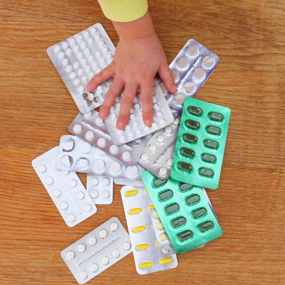 Child reaching toward multiple blister packs of Compounded Medicine, highlighting the importance of pediatric compounding pharmacies in creating child-friendly, customized medications with accurate dosages and improved safety.